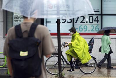 Personas frente a una cartelera financiera en Tokio el 16 de junio del 2021.  (Foto AP/Eugene Hoshiko)