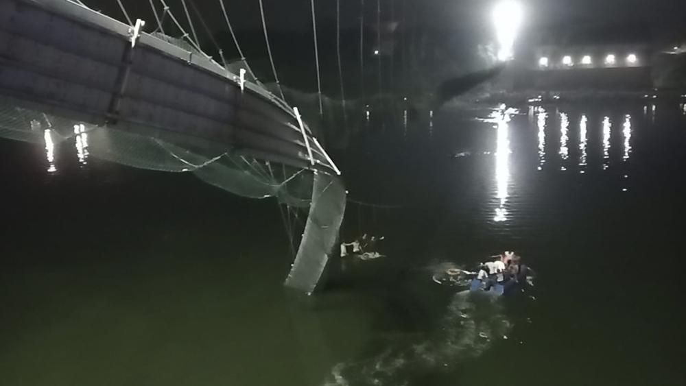 Rescatistas en botes buscan a personas en el río Machchu debajo de un puente que se vino abajo el domingo 30 de octubre de 2022, en el distrito de Morbi, India.  (Foto AP/Rajesh Ambaliya)