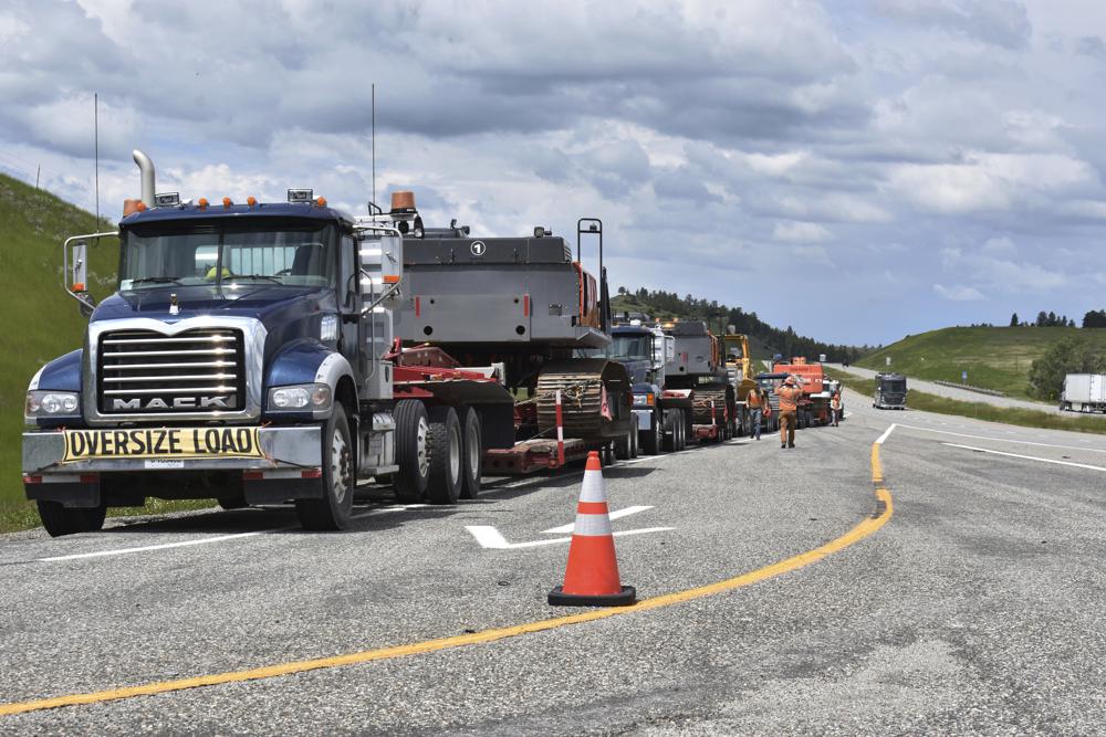 Local authorities are on the scene as heavy equipment is staged to begin removing the wreckage after a bridge collapse near Columbus, Mont., on Saturday, June 24, 2023. The bridge collapsed overnight, causing a train that was traveling over it to plunge into the water below. (AP Photo/Matthew Brown)