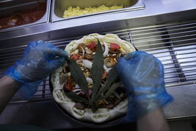 Colocan una hoja de cannabis en una pizza en un restaurante, Bangkok, Tailandia, 24 de noviembre de 2021. The Pizza Company, una gran cadena tailandesa de comidas rápidas, está promocionando su "pizza loca feliz", un producto cubierto con una hoja de cannabis. Es legal, pero no te drpga. (AP Foto/Sakchai Lalit)