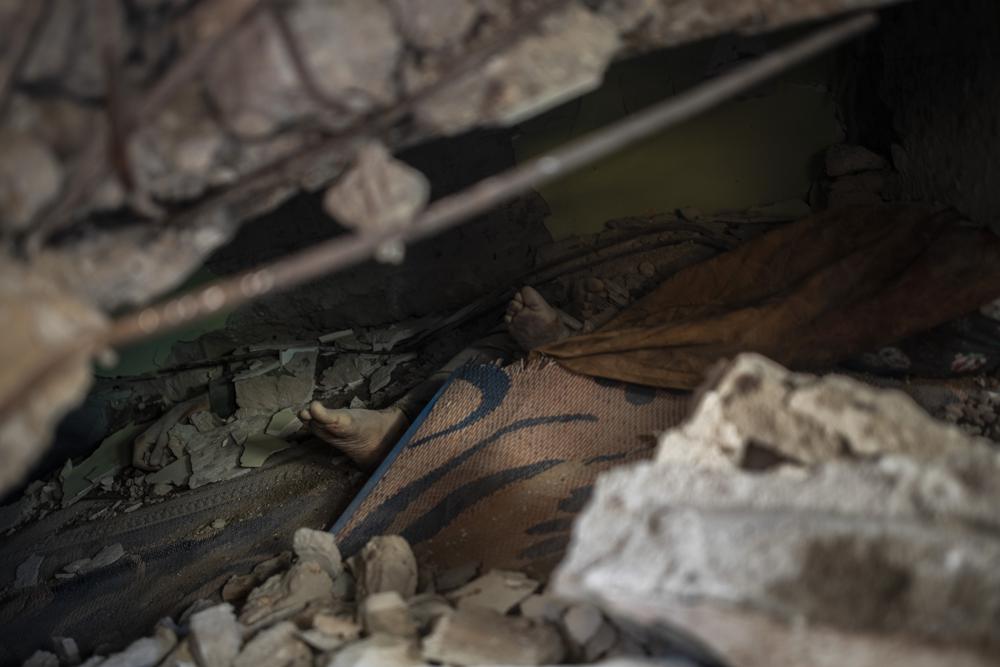 File - In this Sunday, May 16, 2021 file photo, bodies of members of al-Kawlak family lie under the rubble of one of the destroyed residential buildings following deadly Israeli airstrikes in Gaza City. The single deadliest bombing raid of Israel's fourth war with Hamas collapsed two apartment buildings and killed 22 members of the extended al-Kawlak family, including a 6-month-old boy and his 89-year-old great-grandfather (AP Photo/Khalil Hamra,File)