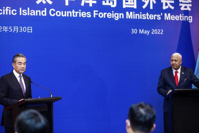 El ministro de Relaciones Exteriores de China, Wang Yi, a la izquierda, aparece en el escenario en la reunión de ministros de Relaciones Exteriores de las Islas del Pacífico con el primer ministro de Fiji, Frank Bainimarama, el lunes 30 de mayo de 2022, en Suva, Fiji. (Leon Lord/Fiji Sun vía AP)