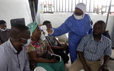 Una enfermera toma la temperatura de personas que se aprestan a recibir la vacuna de Moderna contra el coronavirus en Lagos, Nigeria, 25 de agosto de 2021. (AP Foto/Sunday Alamba)