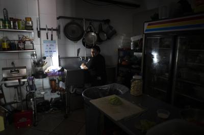 ARCHIVO - Trabajadores de Las Palmas Cafe trabajan con la energía de un generador de electricidad durante un apagón en toda la isla, en San Juan, Puerto Rico, el 7 de abril de 2022. (AP Foto/Carlos Giusti, Archivo)