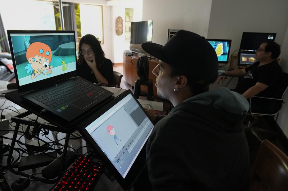 Adrián Díaz, centro, Ginette Hernández, izquierda, y Leonardo Gimón, derecha, trabajan en la creación del primer capítulo de una serie infantil animada llamada Kam-Bur, en un departamento en Caracas, Venezuela, el viernes 1 de julio de 2022. La serie protagonizada por una heroína femenina con rasgos andróginos es dirigida a niños de entre 7 y 12 años en un país donde la creación de este tipo de dibujos es casi nula. (Foto AP/Ariana Cubillos)