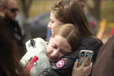 Dos mujeres se abrazan tras un tiroteo escolar en la escuela East High School el miércoles 22 de marzo de 2023, en Denver. Un cuerpo apareció el miércoles por la noche en los bosques de Colorado cerca del auto abandonado de un estudiante de 17 años acusado de disparar ese día a dos trabajadores en su escuela secundaria de Denver, según el jefe de la policía del condado.. (AP Foto/David Zalubowski)