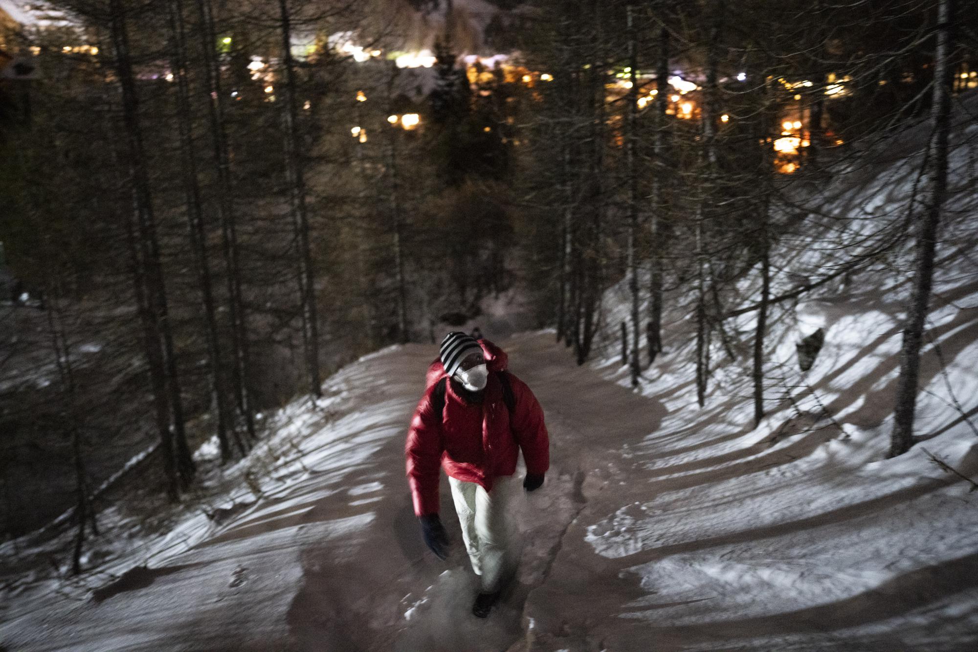 A migrant from Guinea headed to France treks into the mountains by the Italian border town of Claviere in an attempt to cross the border undetected at night, Saturday, Dec. 11, 2021. (AP Photo/Daniel Cole)