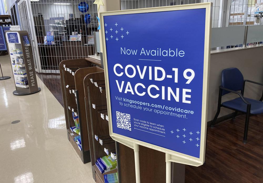 In this Saturday, Oct. 23, 2021, photograph, a sign notifies customers that COVID-19 vaccinations are available at a pharmacy in a grocery store in Monument, Colo. Millions of U.S. workers now have a Jan. 4 deadline to get a COVID vaccine. The federal government on Thursday, Nov. 4, 2021 announced new vaccine requirements for workers at companies with more than 100 employees as well as workers at health care facilities that treat Medicare and Medicaid patients. (AP Photo/David Zalubowski)