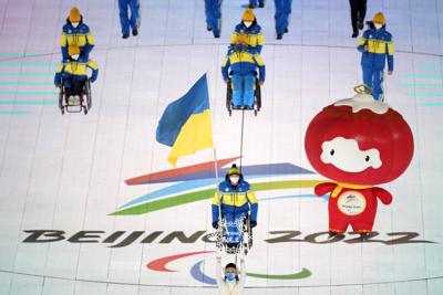 Maksym Yarovyi of Ukraine carries the flag as the team makes their entrance during the opening ceremony at the 2022 Winter Paralympics, Friday, March 4, 2022, in Beijing. (AP Photo/Dita Alangkara)