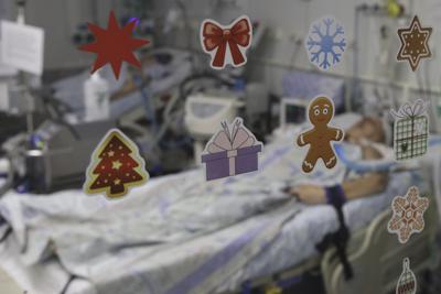 Un paciente con COVID-19 visto a través de una puerta de vidrio decorada con pegatinas navideñas, en la UCI del hospital clínico regional 1, en Krasnodar, en el Sur de Rusia, el 2 de noviembre de 2021. (AP Foto / Vitali Timkiv )