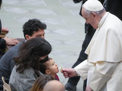 El papa Francisco juega con un bebé durante su audiencia general semanal en la Sala Paulo VI del Vaticano, 23 de febrero de 2022. (AP Foto/Gregorio Borgia)