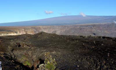 Archivo - El volcán Mauna Loa, al fondo, eclipsa la cumbre del volcán Kilauea (al centro) en el parque nacional de los volcanes en Hawai el 25 de abril de 2019. (AP Foto/Caleb Jones, Archivo)