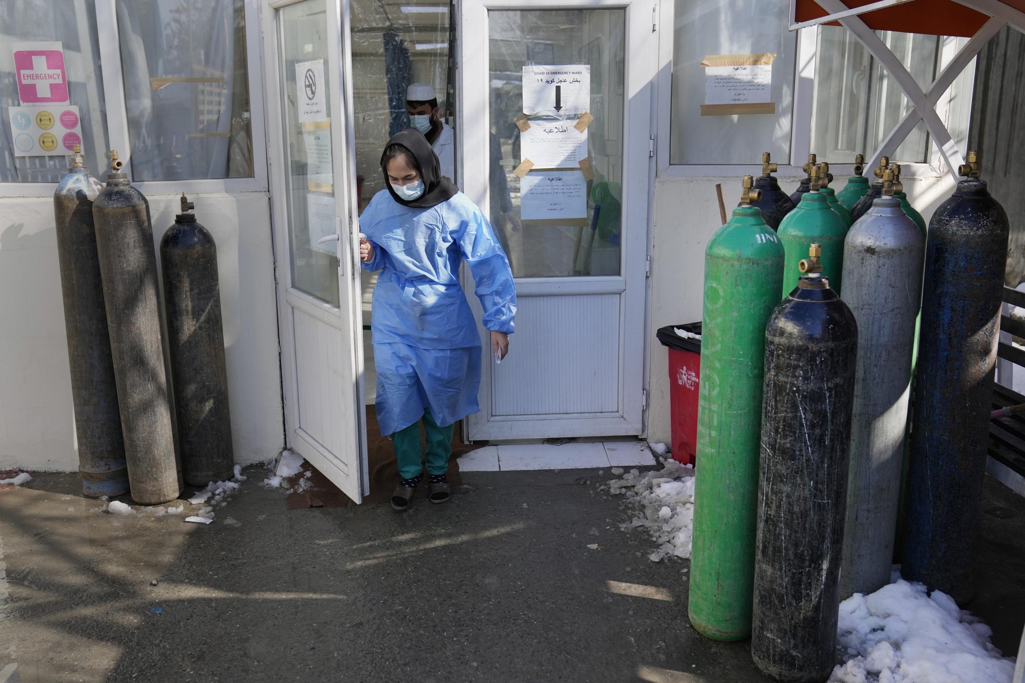 A nurse exits the COVID-19 intensive care unit of the Afghan Japan Communicable Disease Hospital, in Kabul, Afghanistan, Monday, Feb. 7, 2022. All but five of 38 COVID treatment hospitals that once operated in Afghanistan have been forced to close for lack of doctors, medicines and even heat. This comes as an economically devastated Afghanistan last week experienced a 67% increase in the numbers of reported COVID cases, according to the World Health Organization. (AP Photo/Hussein Malla)