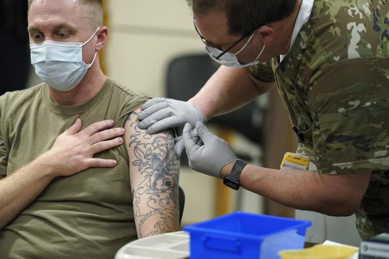 FILE - Staff Sgt. Travis Snyder, left, receives the first dose of the Pfizer COVID-19 vaccine given at Madigan Army Medical Center at Joint Base Lewis-McChord in Washington state, Dec. 16, 2020, south of Seattle. The Army says 98% of its active duty force had gotten at least one dose of the mandatory coronavirus vaccine as of this week’s deadline for the shots.  (AP Photo/Ted S. Warren, File)