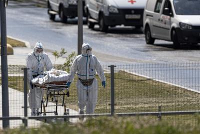 Trabajadores médicos llevan en una camilla a un paciente sospechoso de tener virus a un hospital en Kommunarka, en las afueras de Moscú, Rusia, el sábado 26 de junio de 2021. (AP Foto/Alexander Zemlianichenko)