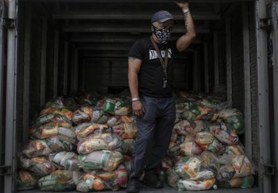 ARCHIVO - En esta fotografía de archivo del 10 de abril de 2021, un hombre espera para descargar bolsas de alimentos básicos básicos, como pasta, azúcar, harina y aceite de cocina, entregados a los residentes a través del programa de asistencia alimentaria del gobierno CLAP en el barrio Santa Rosalía de Caracas, Venezuela. (AP Foto/Matias Delacroix, Archivo)