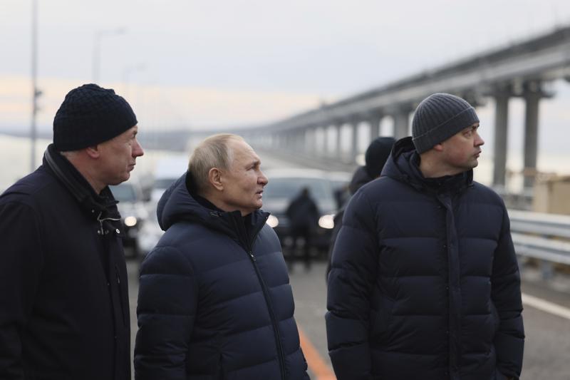 Russian President Vladimir Putin, center, and Deputy Prime Minister Marat Khusnullin, left, visit the Crimean Bridge connecting Russian mainland and Crimean peninsula over the Kerch Strait, which was damaged by a truck bomb attack in October, after restoration works, not far from Kerch, Crimea, Monday, Dec. 5, 2022. (Mikhail Metzel, Sputnik, Kremlin Pool Photo via AP)