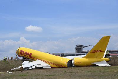 Un avión de carga yace roto en la pista del Aeropuerto Internacional Juan Santamaría en Alajuela, Costa Rica, el jueves 7 de abril de 2022. Según el departamento de bomberos, tanto el piloto como el copiloto se reportan en buen estado de salud y el accidente provocó el cierre total de la terminal aérea. (AP Foto/Carlos Gonzalez)