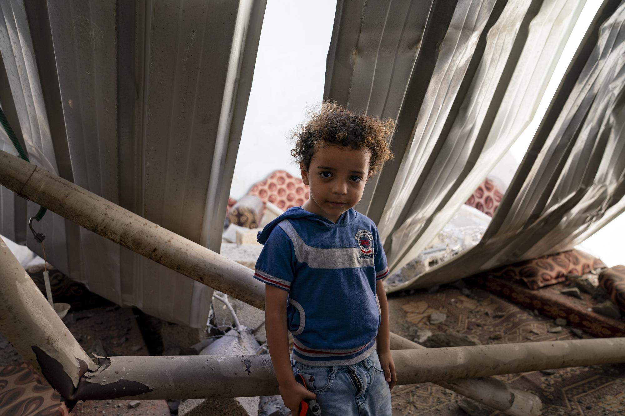 Mohammad Ismail, 4, sits for a portrait in his bedroom that was damaged when an airstrike destroyed a nearby building prior to a cease-fire that halted an 11-day war between Gaza's Hamas rulers and Israel, Thursday, May 27, 2021, in Maghazi, Gaza Strip. (AP Photo/John Minchillo)