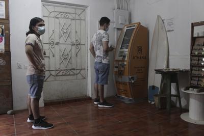 Eduardo Magaña (derecha) utiliza el primer cajero automático diseñado para retirar efectivo a través de la aplicación de criptomonedas Bitcoin Beach, el miércoles 9 de junio de 2021 en la playa El Zonte, en Tamanique, El Salvador. (AP Foto/Salvador Meléndez)