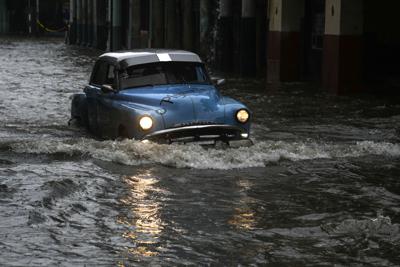 Una persona conduce un automóvil clásico estadounidense por una calle inundada por fuertes lluvias, en La Habana, Cuba, el viernes 3 de junio de 2022. (AP Foto/Ramon Espinosa)