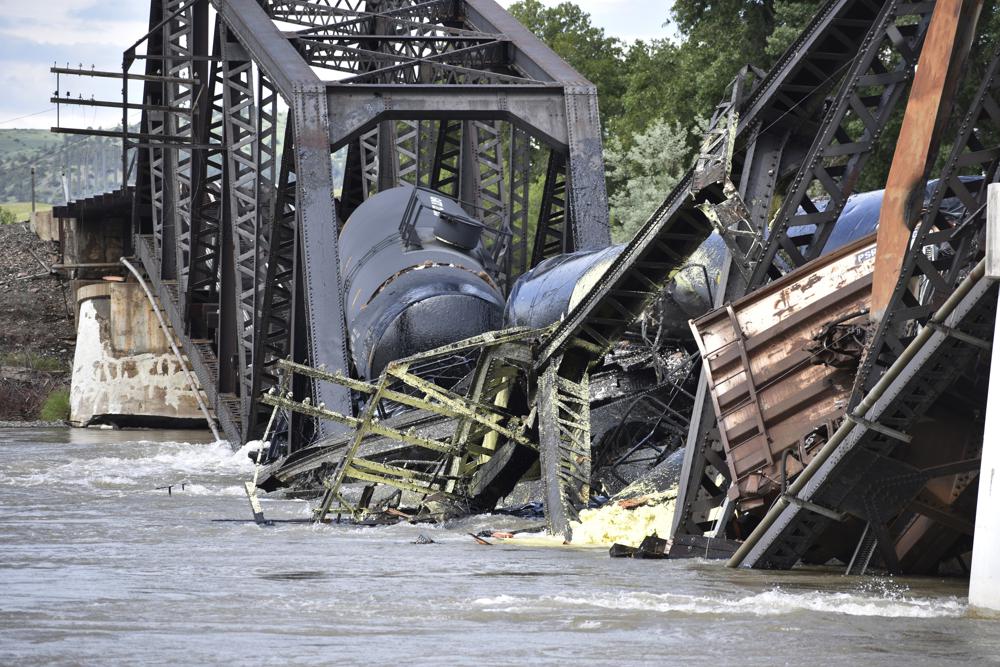 Several train cars are immersed in the Yellowstone River after a bridge collapse near Columbus, Mont., on Saturday, June 24, 2023. The bridge collapsed overnight, causing a train that was traveling over it to plunge into the water below. (AP Photo/Matthew Brown)