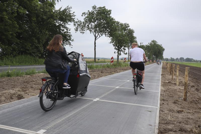 People use the solar cycle path in Maartensdijk, Netherlands, Wednesday, July 14, 2021. The cycle path was launched on the day the European Union unveiled sweeping new legislation to help meet its pledge to cut emissions of the gases that cause global warming by 55% over this decade, including a controversial plan to tax foreign companies for the pollution they cause. (AP Photo/Aleksandar Furtula)