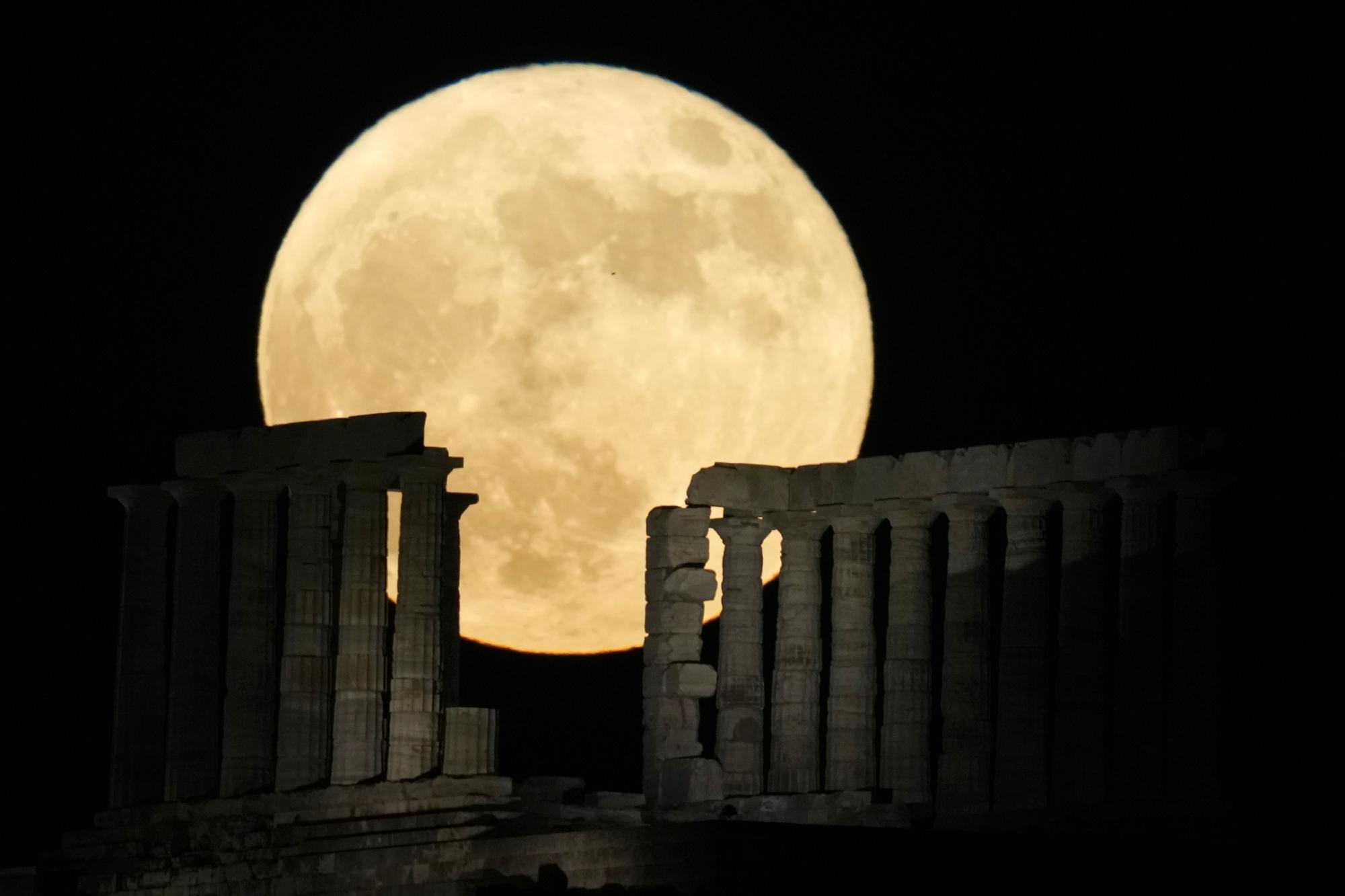 The strawberry full moon rises behind the ancient temple of Poseidon at Cape Sounion, about 70 kilometers (45 miles) south of Athens, Greece, Tuesday, June 14, 2022. The moon reach its full stage on Tuesday, during a phenomenon known as a supermoon because of its proximity to Earth, and it is also labeled as the "Strawberry Moon" because it is the full moon at strawberry harvest time. (AP Photo/Thanassis Stavrakis)