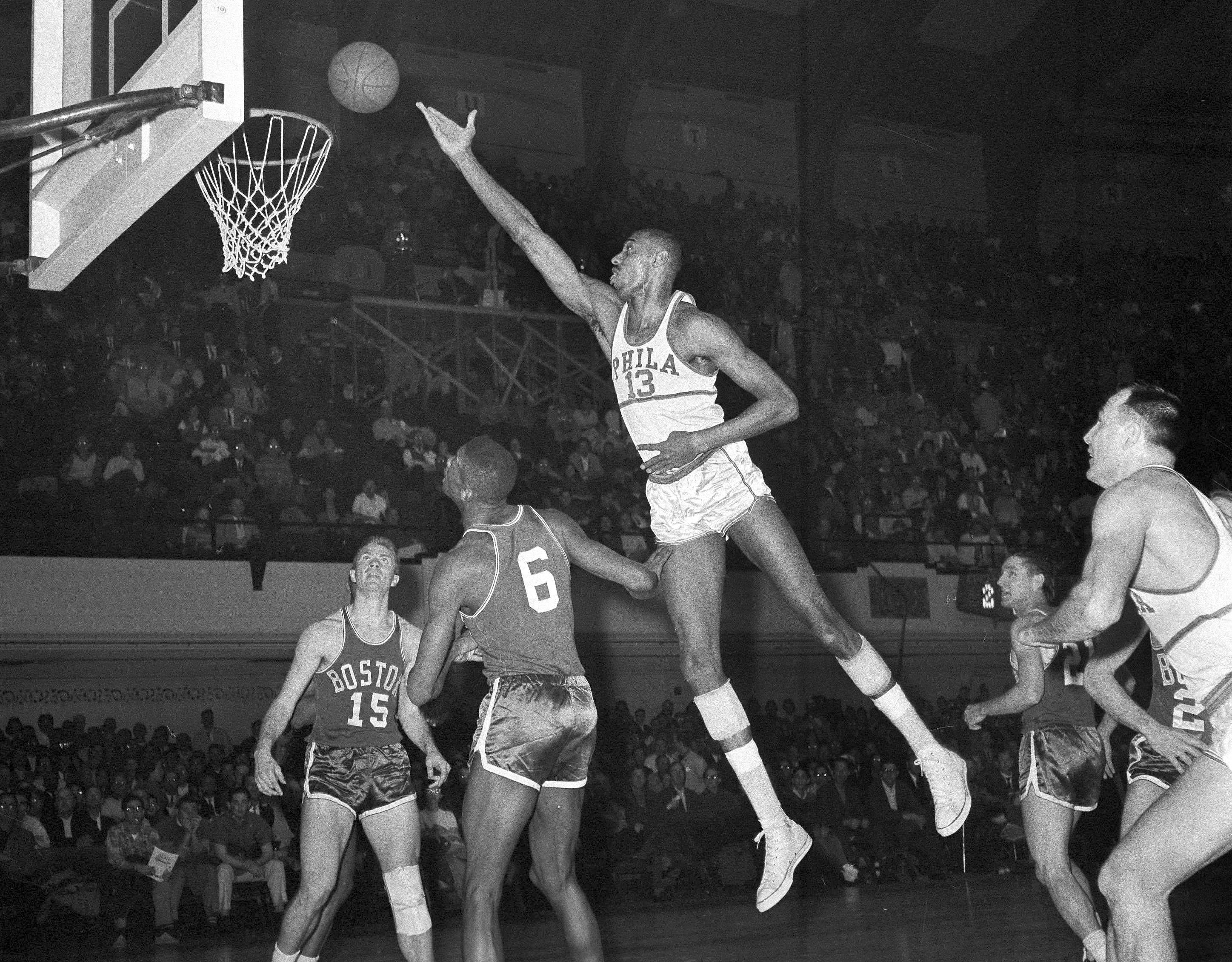 Free Photo  Black professional basketball player holds a ball over the  hoop in a game hall.