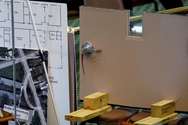 A section of a classroom door from Robb Elementary School in Uvalde, Texas, is seen as Texas Department of Public Safety Director Steve McCraw testifies at a Texas Senate hearing at the state capitol, Tuesday, June 21, 2022, in Austin, Texas. Two teachers and 19 students were killed in last month's mass shooting in Uvalde. (AP Photo/Eric Gay)