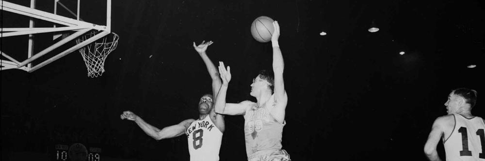 George Mikan, right, six-foot, ten-inch center for the Minneapolis Lakers, goes way up to make a goal as New York Knickerbockers' six-foot, seven-inch center Nat "Sweetwater" Clifton (8) makes an unsuccessful attempt to defend on April 8, 1953 at the 69th Regiment Armory in New York. (AP Photo)