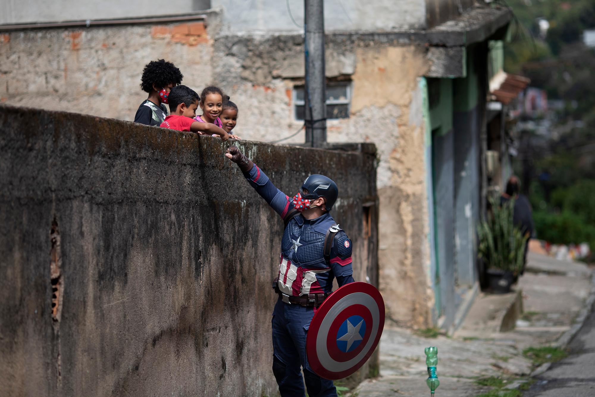 Military police officer Everaldo Pinto, dressed as superhero Captain America, greets children and encourages them to protect themselves during the COVID-19 pandemic in Petropolis, Rio de Janeiro state, Brazil, on April 15, 2021. (AP Photo/Silvia Izquierdo)