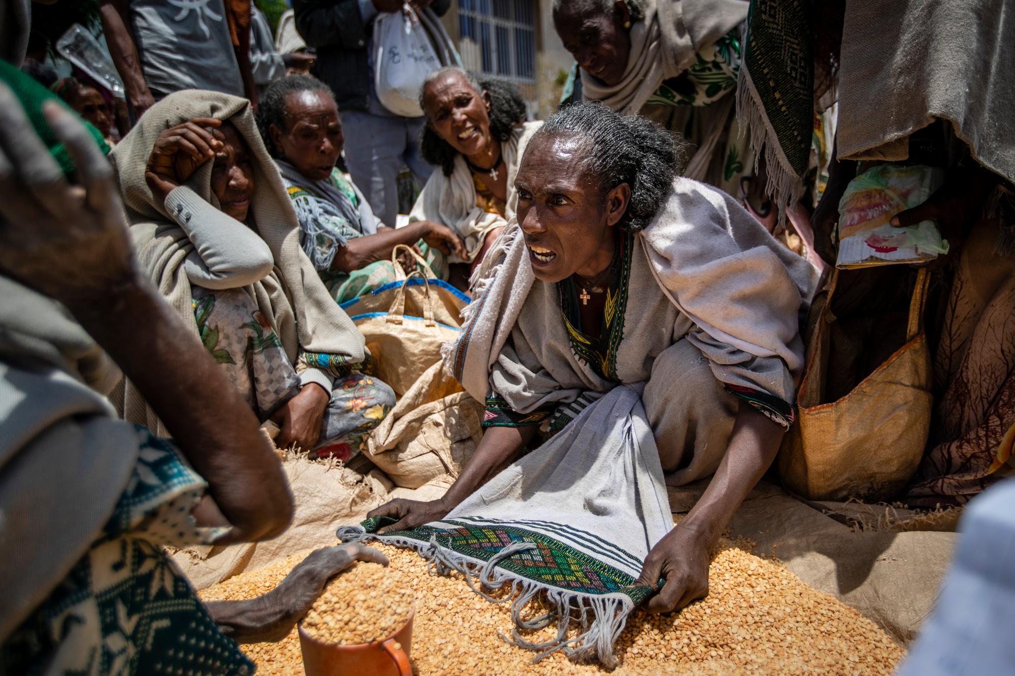 An Ethiopian woman argues with others over the allocation of yellow split peas distributed by the Relief Society of Tigray in the town of Agula, in the Tigray region of northern Ethiopia, on May 8, 2021. In war-torn Tigray, it is not just that people are starving; it is that many are being starved, The Associated Press found. (AP Photo/Ben Curtis)