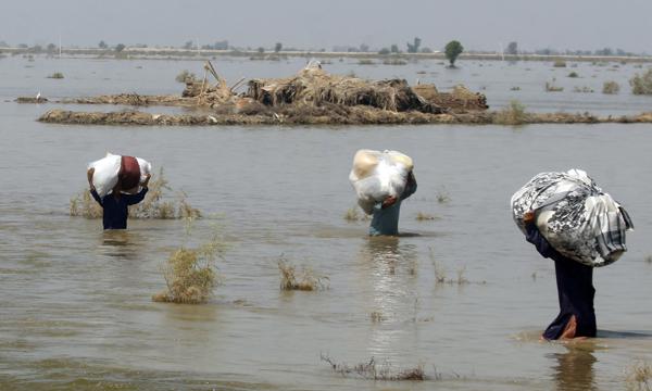 Victims of heavy flooding from monsoon rains crowd carry relief aid through flood water in the Qambar Shahdadkot district of Sindh Province, Pakistan, Friday, Sept. 9, 2022. U.N. Secretary-General Antonio Guterres appealed to the world for help for cash-strapped Pakistan after arriving in the country Friday to see the climate-induced devastation from months of deadly record floods. (AP Photo/Fareed Khan)