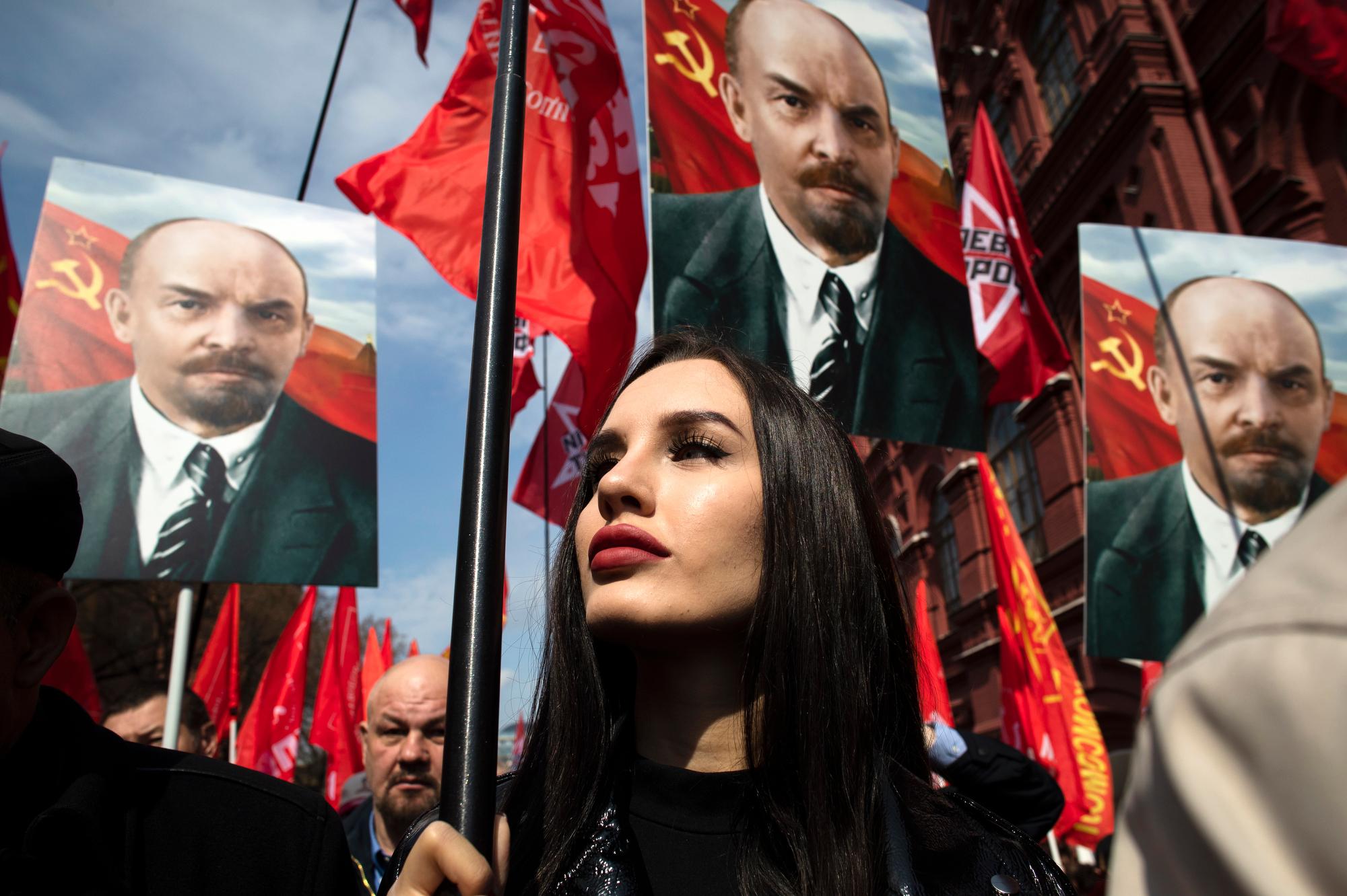 Russian communist supporters hold flags and portraits of Vladimir Lenin as they walk to the mausoleum housing the Soviet founder’s remains to mark the 151st anniversary of his birth on April 22, 2021, in Moscow. (AP Photo/Pavel Golovkin)