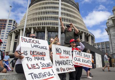 Manifestantes sostienen pancartas en apoyo a una caravana de vehículos que bloquea el Parlamento de Nueva Zelanda, el martes 8 de febrero de 2022, en Wellington. (Mark Mitchell/New Zealand Herald vía AP)