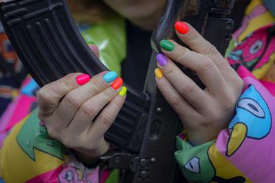 Una joven maneja un arma durante un combate para entrenar a civiles, en Mariupol, en la región de Donetsk, Ucrania, el domingo 13 de febrero de 2022. (AP Foto/Vadim Ghirda)