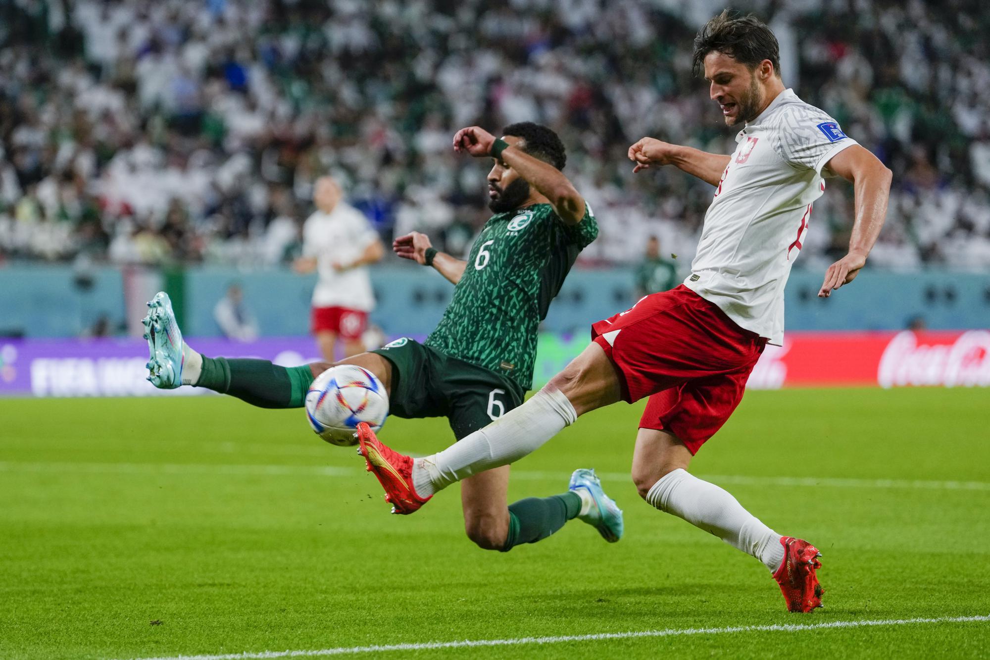 Saudi Arabia's Mohammed Al-Burayk tries to block a shot from Poland's Bartosz Bereszynski soccer match between Poland and Saudi Arabia, at the Education City Stadium in Al Rayyan , Qatar, Saturday, Nov. 26, 2022. (AP Photo/Manu Fernandez)