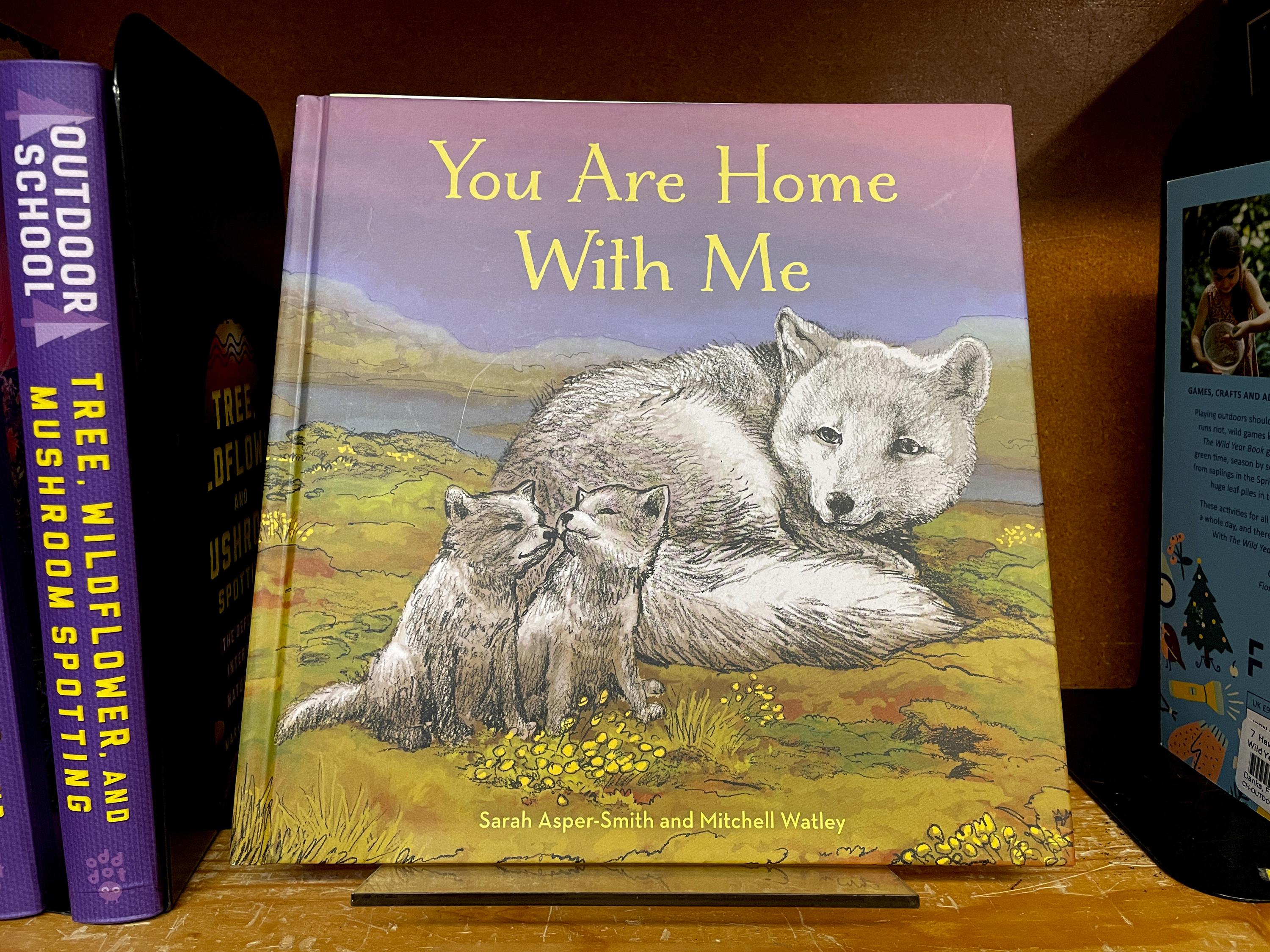 The children's book "You Are Home With Me," illustrated by Mitchell Thomas Watley, is shown at a bookstore in Portland, Ore. in this April 5, 2023 photo. Publisher Sasquatch books, owned by Penguin Random House, said Wednesday, April 5, 2023, it has ended its publishing relationship with Watley after he was arrested on allegations of leaving violent, transphobic notes in stores around Juneau, Alaska. Watley told police he was motivated by fear following a deadly school shooting in Nashville that sparked online backlash about the shooter's gender identity, court records show. (AP Photo/Claire Rush)