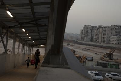 ARCHIVO - Una mujer y su hijo caminan por una rampa peatonal el 24 de noviembre de 2021 en dirección a Cisjordania desde Jerusalén, junto al lugar donde Israel planeaba construir un enorme asentamiento judío en un aeropuerto abandonado. (AP Foto/Maya Alleruzzo, archivo)