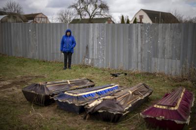 Ira Slepchenko, de 54 años, observa cuatro féretros, uno de ellos con el cuerpo de su esposo Sasha Nedolezhko, de 43 años, durante una exhumación de una fosa común, el domingo 17 de abril de 2022, en Mykulychi, Ucrania. (AP Foto/Emilio Morenatti)