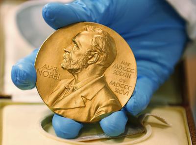 En esta imagen de archivo, tomada el 17 de abril de 2015, un empleado de la biblioteca nacional muestra una medalla de oro del Premio Nobel. (AP Foto/Fernando Vergara, archivo)
