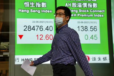 Una persona frente a una cartelera financiera en Hong Kong, el 22 de junioo del 2021. (Foto AP/Kin Cheung)