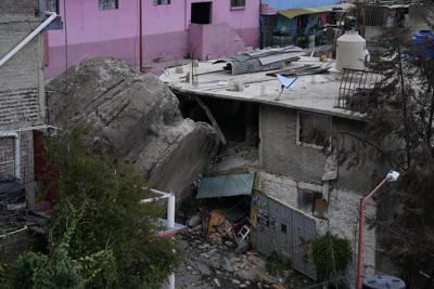 Una de varias rocas gigantescas que se desprendieron de lo alto de un cerro cayó al lado de varias casas en una ladera en la localidad de Tlalnepantla, en las afueras de la Ciudad de México, el viernes 10 de septiembre de 2021. Hay varias víctimas, dicen las autoridades. (AP Foto/Eduardo Verdugo)
