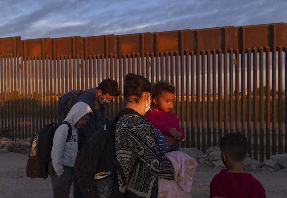 ARCHIVO - Dos familias brasileñas esperan a ser procesadas por la Patrulla de Fronteras de Estados Unidos tras cruzar por un hueco en la cerca fronteriza desde México, en Yuma, Arizona, el jueves 10 de junio de 2021, tras pedir asilo en Estados Unidos. (AP Foto/Eugene Garcia, Archivo)