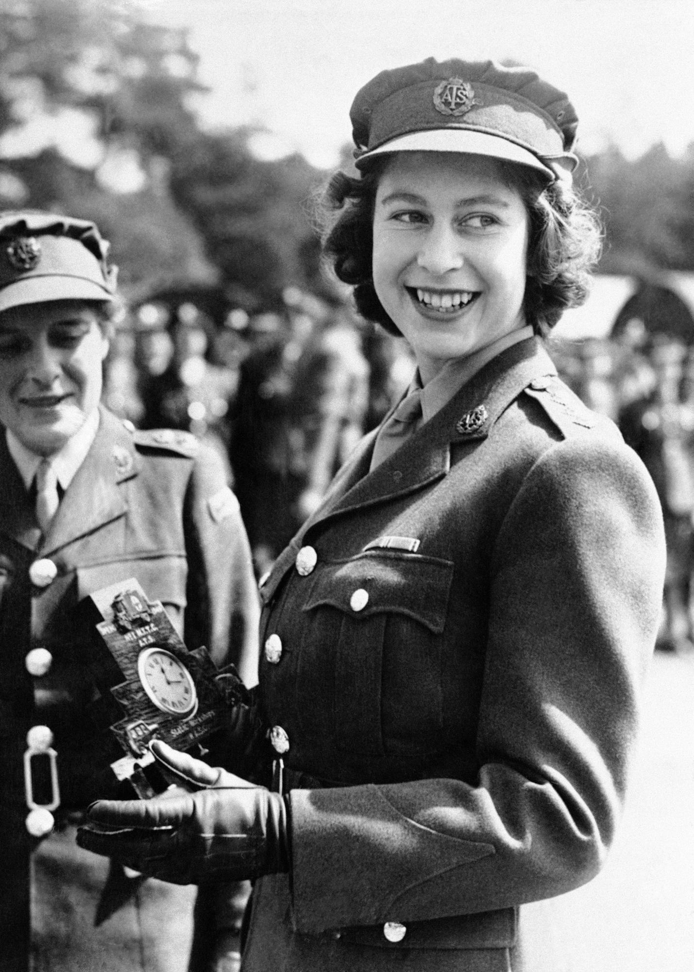 FILE - Britain's Princess Elizabeth, a Junior Commander in the Auxiliary Territorial Service, receives a clock presented to her by her old associates at the camp where she received her early training, during a ceremony at the No. 1 M.T. Training Center, in Camberley, England, Aug. 3, 1945. (AP Photo, File)