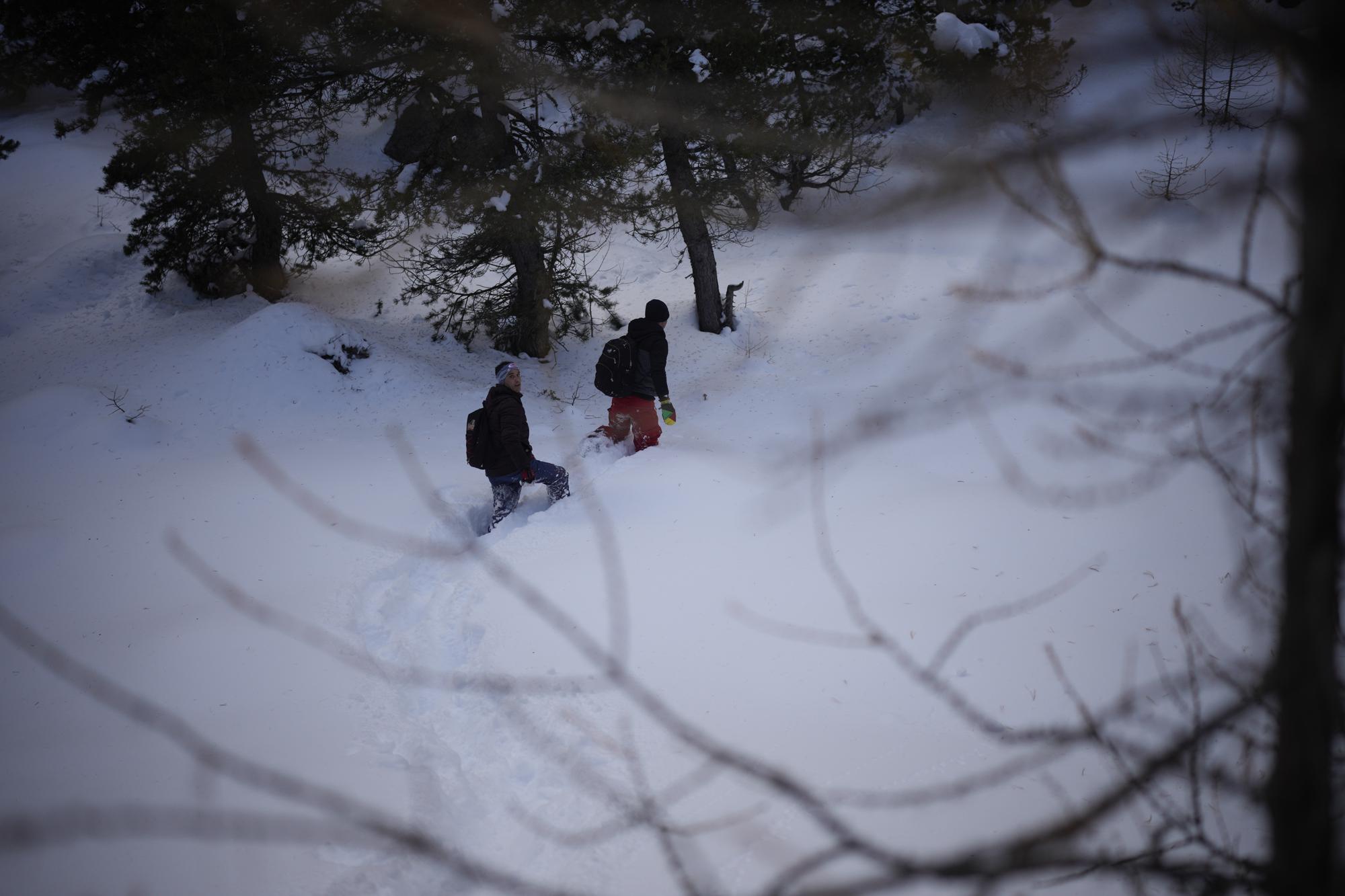 Afghan migrants Ali Rezaie, right, and Sayed Hamza trek through the French-Italian Alps to reach a migrant refuge in Briancon, France, Sunday, Dec. 12, 2021. When the Taliban seized power in Afghanistan in August, some Afghans resolved to escape and embarked on forbidding journeys of thousands of kilometers to Europe. Ali Rezaie's odyssey through five countries has carried him high into the French-Italian Alps, where he is pushing through knee-deep snow to evade border guards. (AP Photo/Daniel Cole)