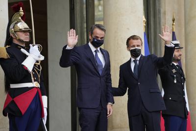 El presidente francés, Emmanuel Macron (izquierda), y el primer ministro griego, Kyriakos Mitsotakis (centro), saludan el martes 28 de septiembre de 2021 en el Palacio del Elíseo en París. (AP Foto/Francois Mori)