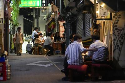 Gente reunida en bares abiertos y que sirven alcohol, en un callejón lleno de bares y restaurantes pese a las peticiones del gobierno de Tokio de que los establecimientos no sirvieran alcohol durante el estado de emergencia, el miércoles 22 de septiembre de 2021 en Tokio. (AP Foto/Kiichiro Sato)