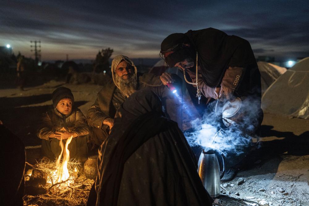 FILE - A family prepares tea outside the Directorate of Disaster office where they are camped, in Herat, Afghanistan, on Nov. 29, 2021. As winter deepens, a grim situation in Afghanistan is getting worse. Freezing temperatures are compounding the misery from the downward spiral that has come with the fall of the U.S.-backed government and the Taliban takeover. Aid groups and international agencies estimate about 23 million people, half the country, face severe hunger and nearly 9 million are on the brink of starvation. (AP Photo/Petros Giannakouris, File)